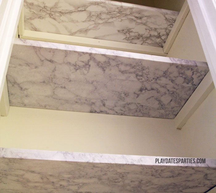 three marbled steps leading up to the top floor in a bathroom with white walls