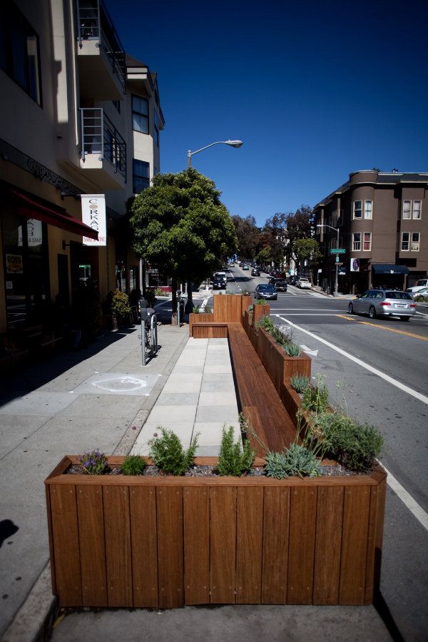 a long wooden planter on the side of a road