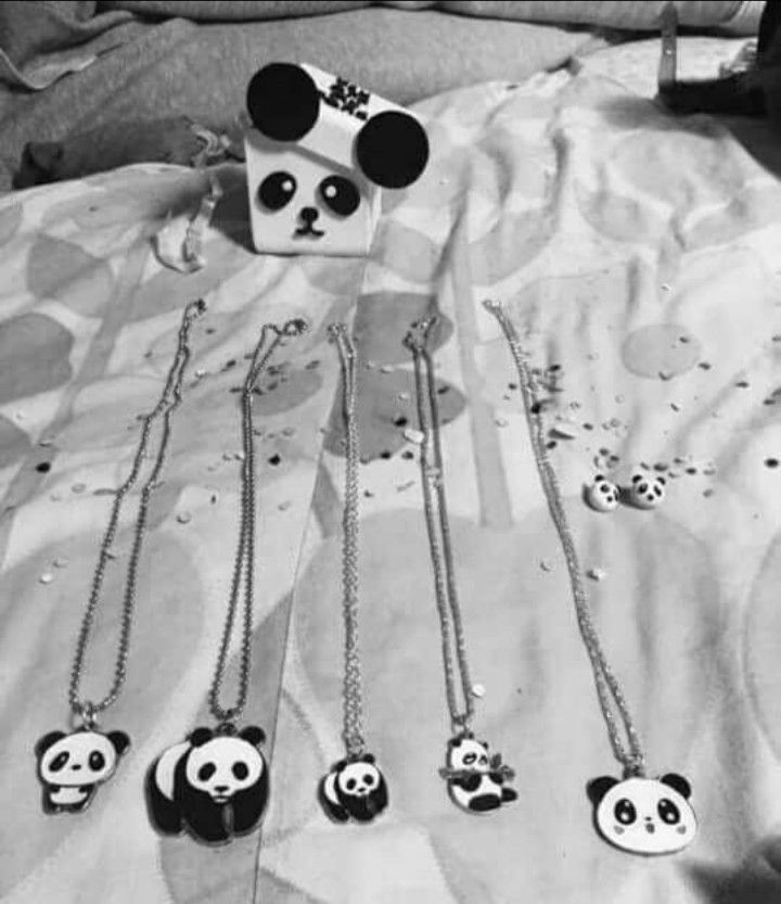 several necklaces with panda faces on them sitting on a bed next to a box