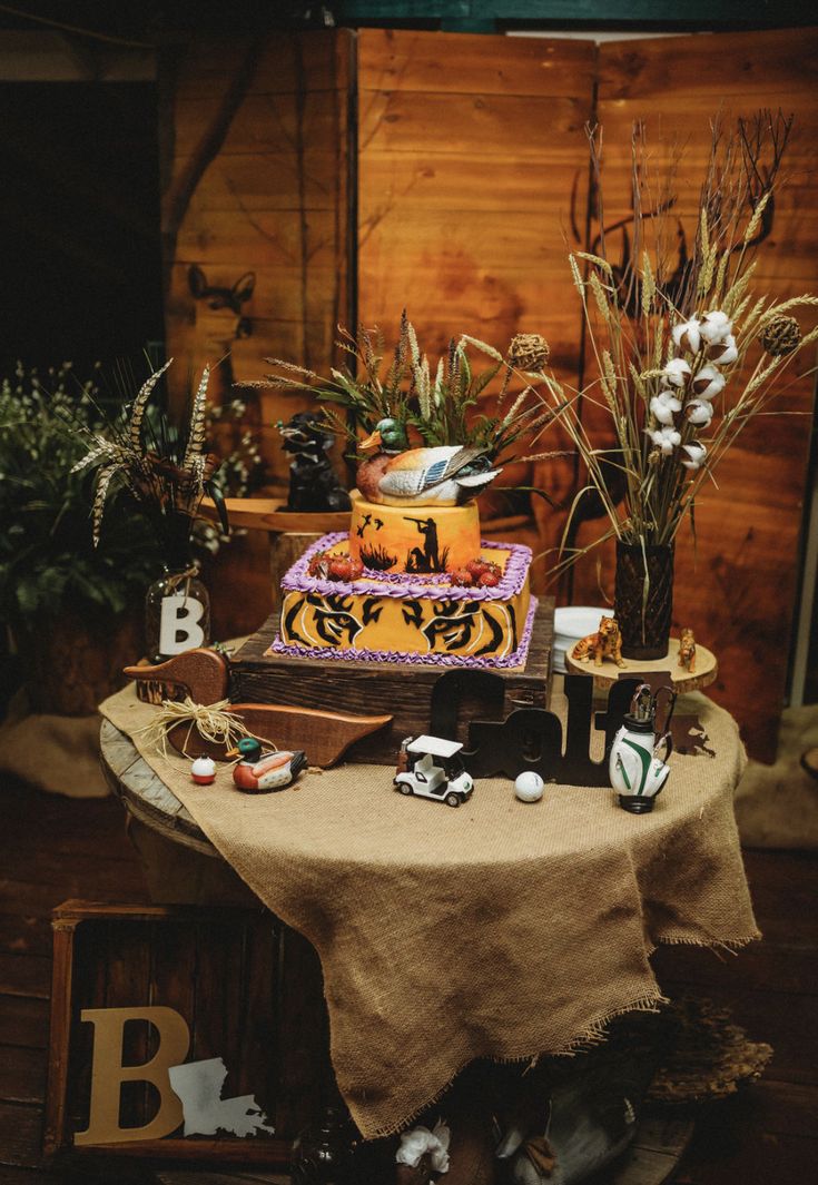 a table topped with a cake covered in frosting next to plants and other decorations