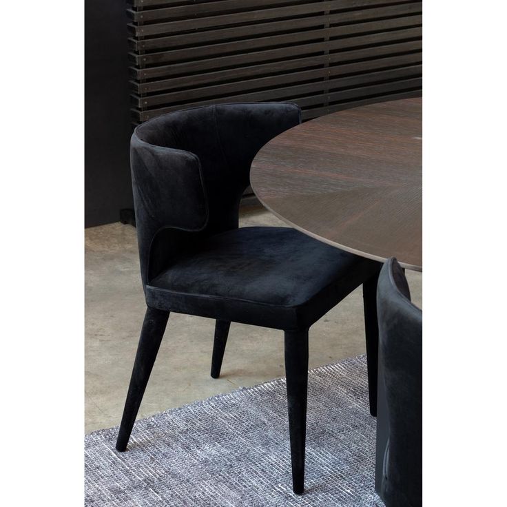 a black chair sitting next to a wooden table on top of a carpeted floor