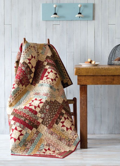 a chair with a quilt on it next to a table and a birdcage