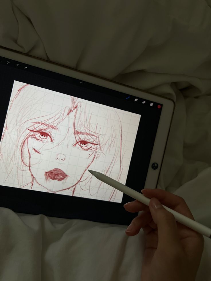 a person is drawing on an ipad with a pencil in their hand while laying down