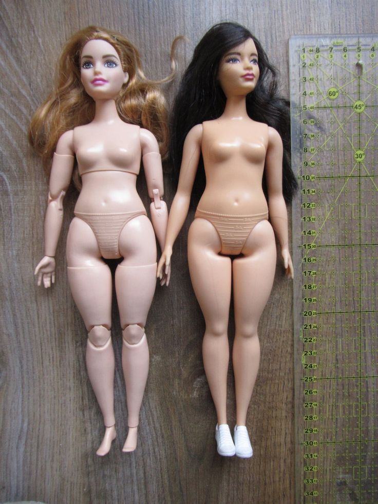 two dolls sitting next to each other on a wooden surface