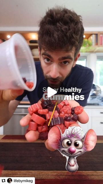 a man holding up a cup filled with gummy bears while looking at the camera