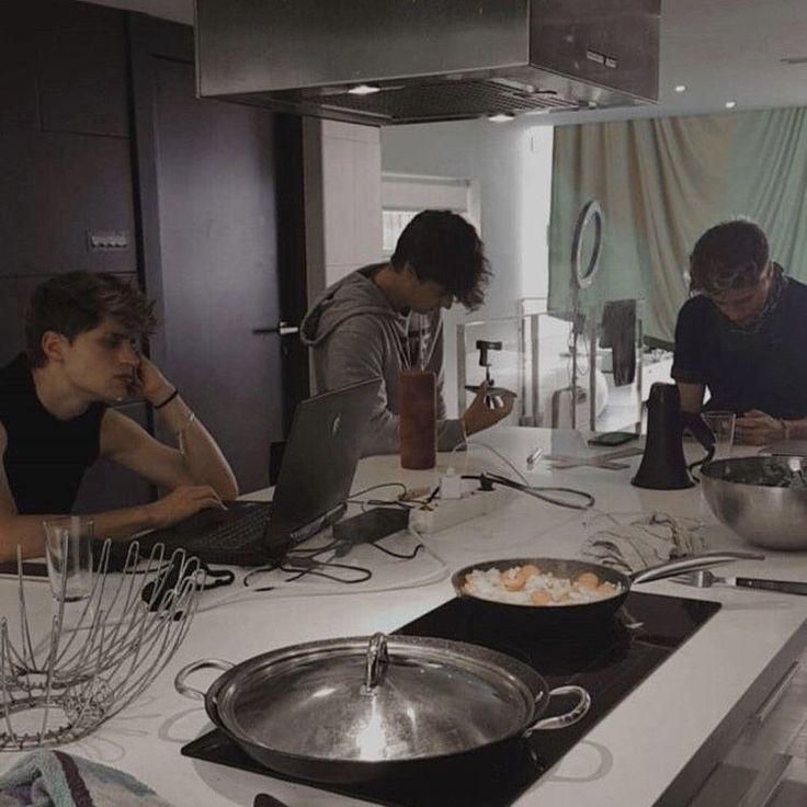 three people in a kitchen preparing food on a stove top with utensils and mixers