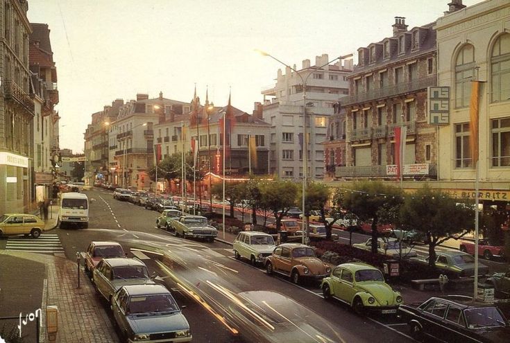 a city street filled with lots of traffic next to tall buildings on either side of the road