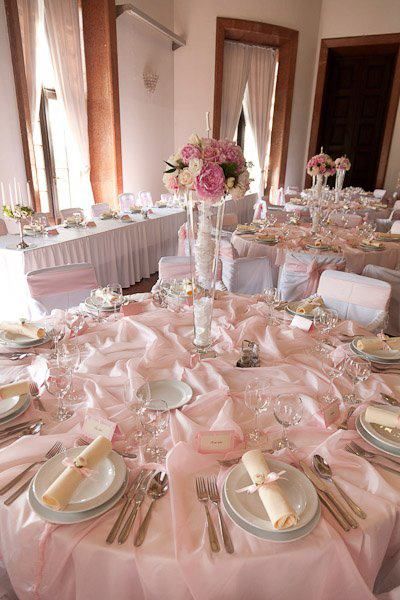 the table is set with pink linens and place settings for formal dinner party guests