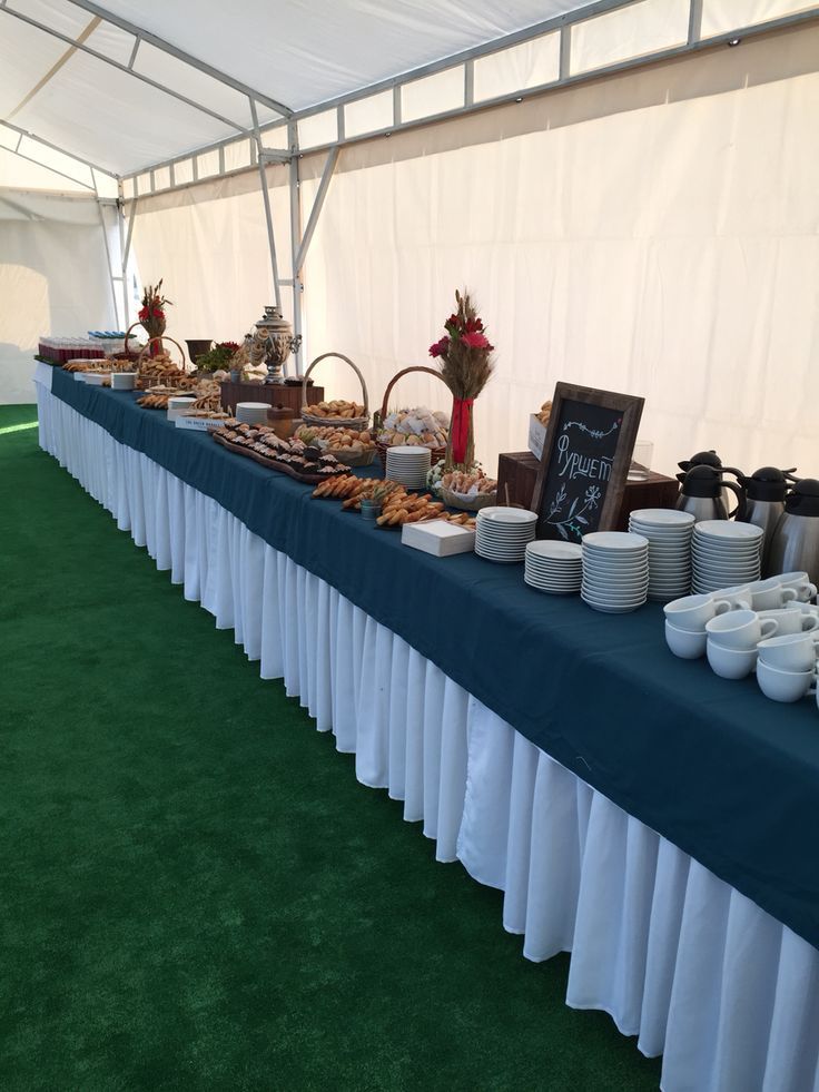 a long table covered in plates and bowls with food on it's sides under a tent