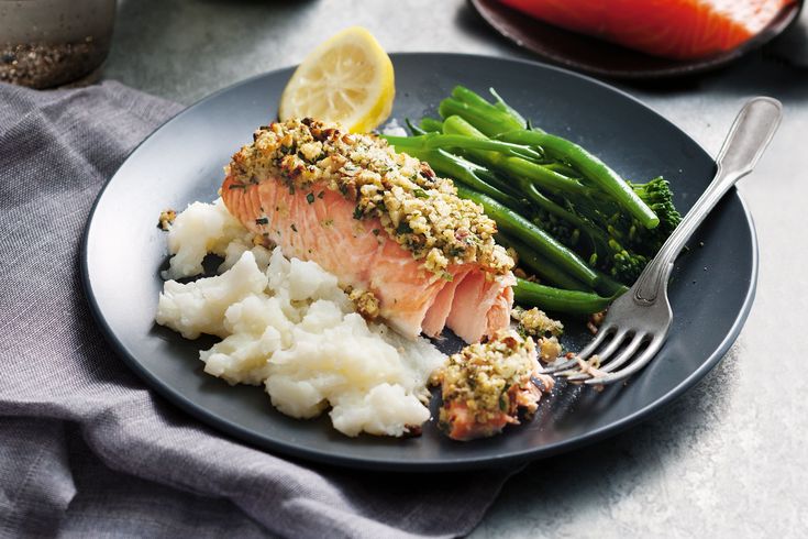 a plate with salmon, mashed potatoes and asparagus next to a fork