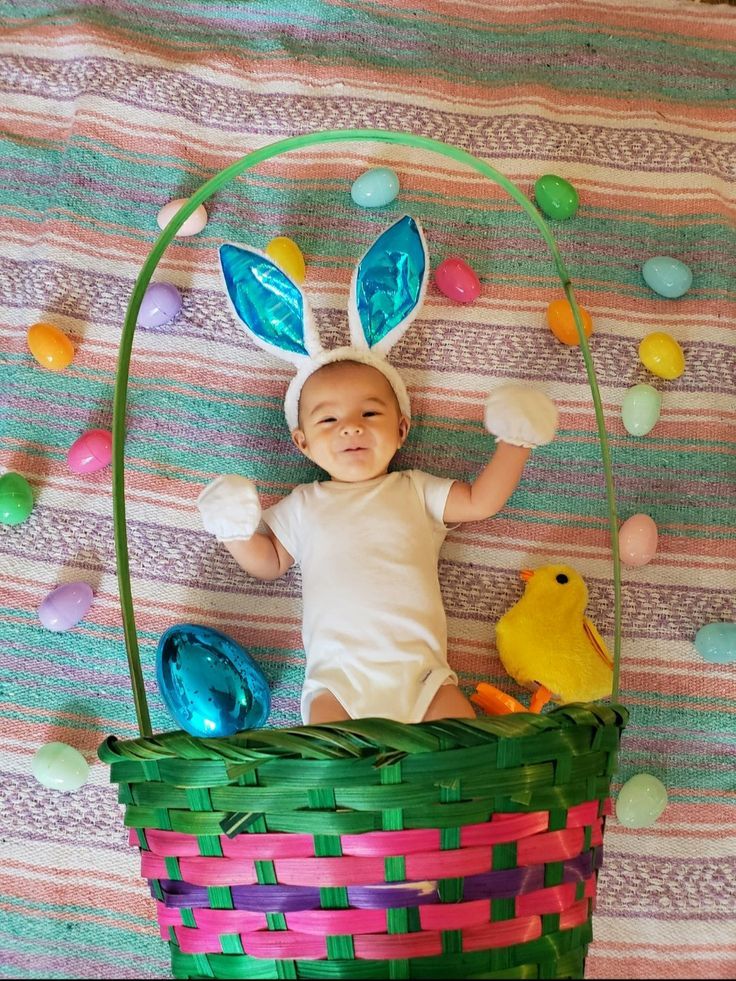 a baby laying in a basket with easter decorations