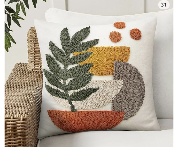 a decorative pillow on a chair next to a wicker basket and potted plant