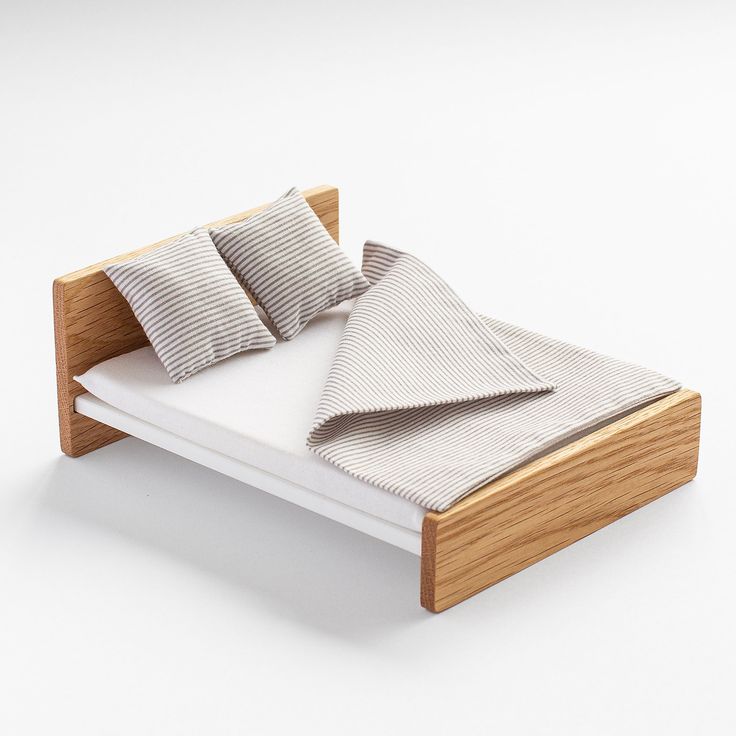 a bed with two pillows on top of it and a blanket folded over the headboard