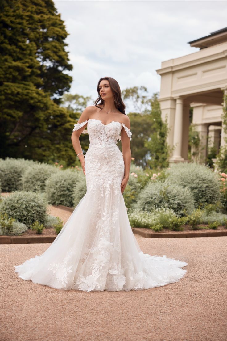 a woman in a white wedding dress standing on the ground with her hands on her hips