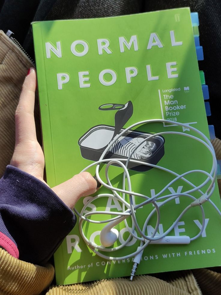 a person holding a book with headphones in their hands and the title normal people