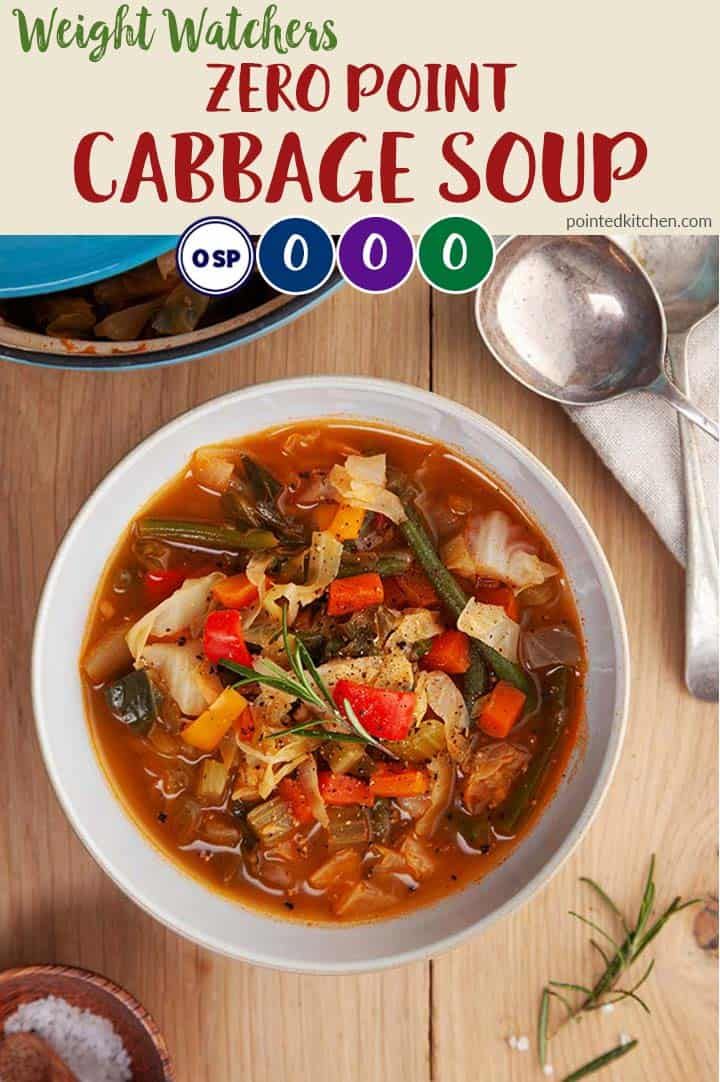 a white bowl filled with vegetable cabbage soup on top of a wooden table next to spoons