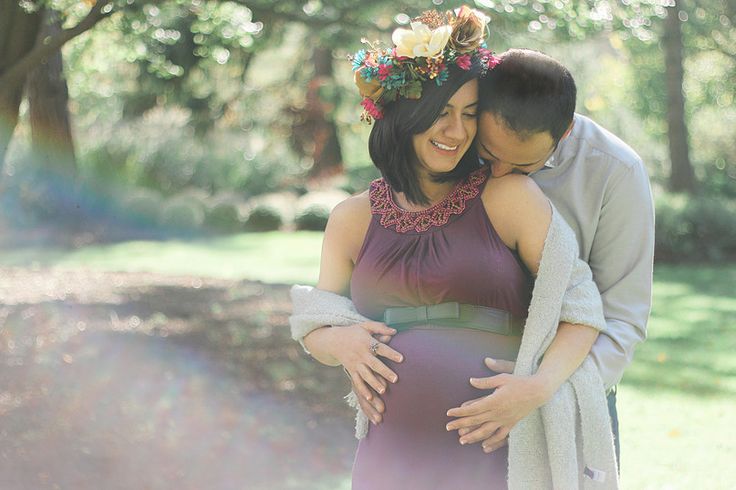 a pregnant woman hugging her husband in the park