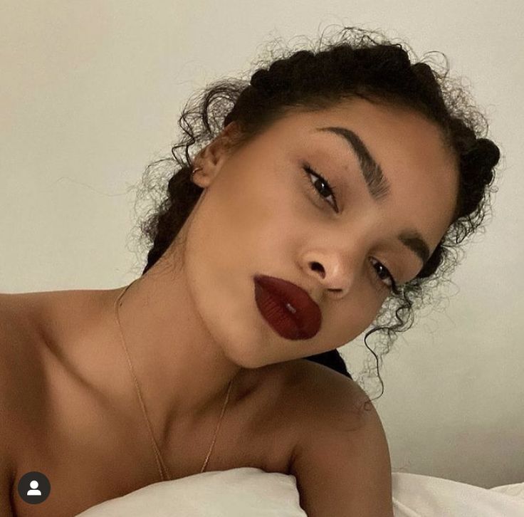 a woman laying on top of a bed wearing red lipstick