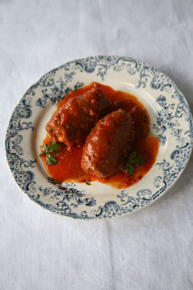 two meatballs covered in marinara sauce on a blue and white plate