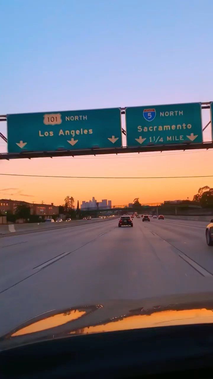 cars driving down the highway in front of an overpass with signs above it that read 101 north and los angeles