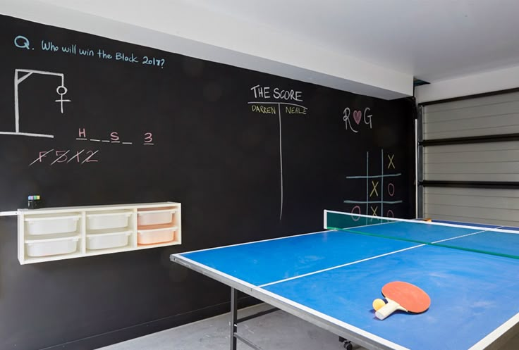 a ping pong table in front of a chalkboard wall