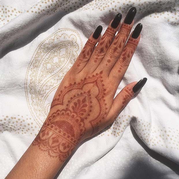 a woman's hand with henna on top of her arm and black nails