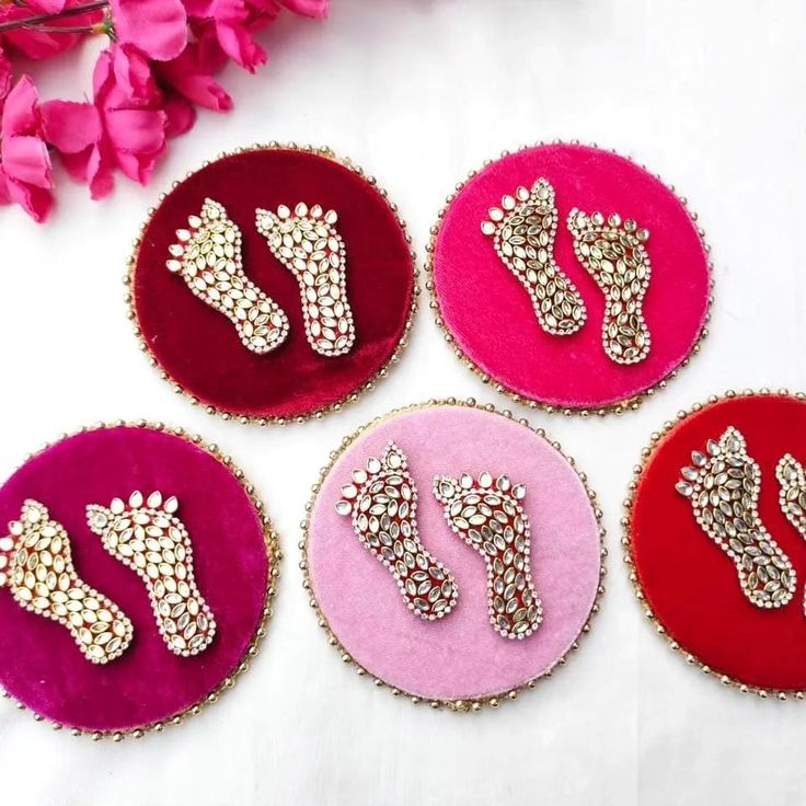 four pairs of pink and red brooches sitting on top of a white table