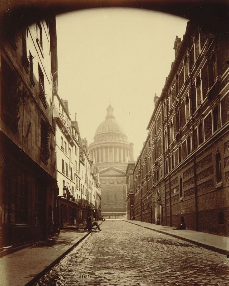 an old photo of a cobblestone street in front of the dome of st paul's cathedral