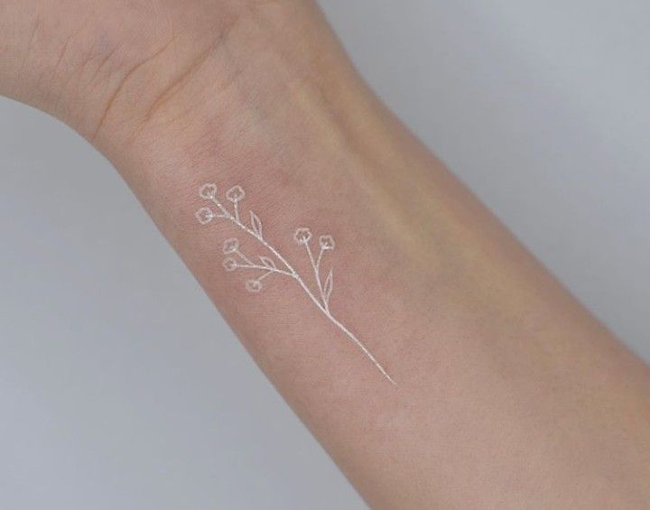 a small white flower tattoo on the wrist