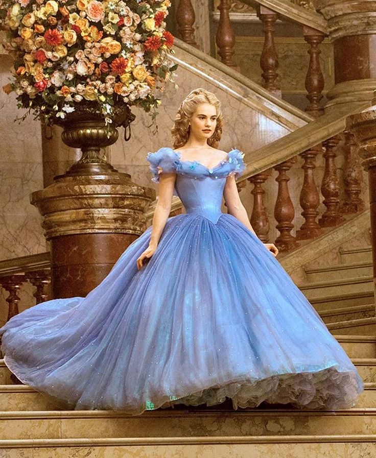 a woman in a blue dress standing on some stairs