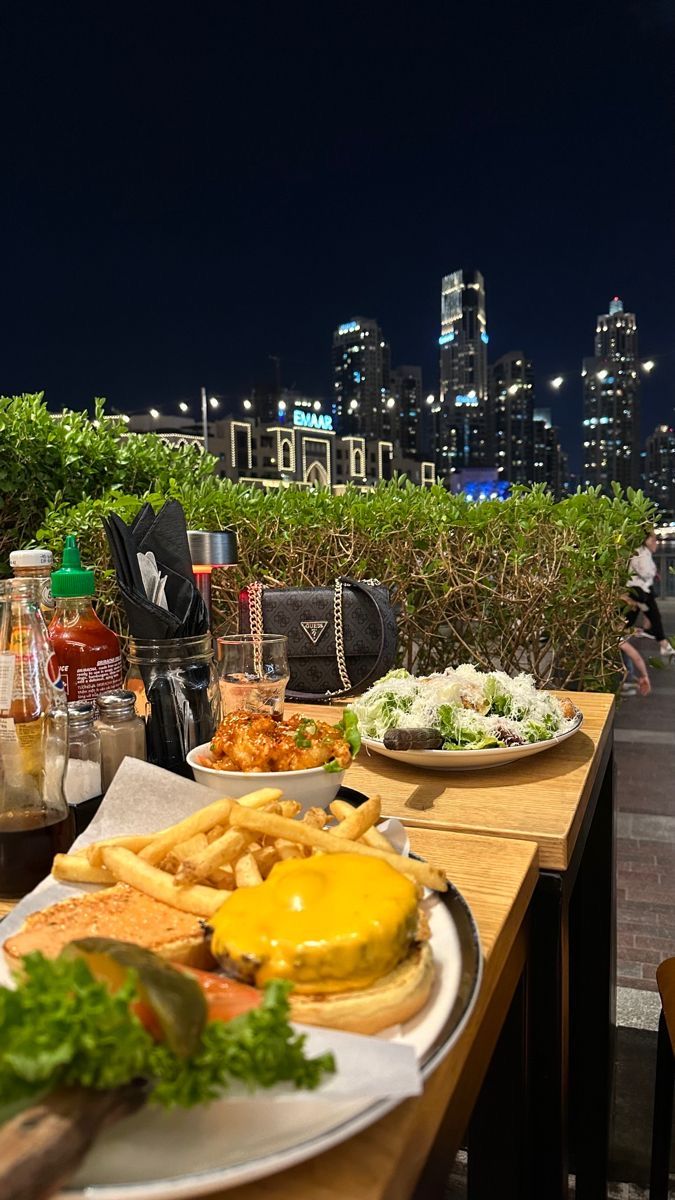 a table with plates of food and drinks on it in front of a cityscape