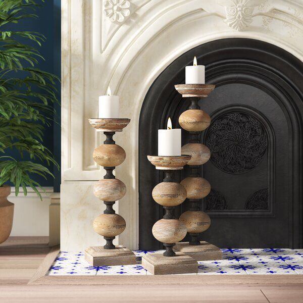 a candle holder made out of wooden balls on a rug in front of a fireplace