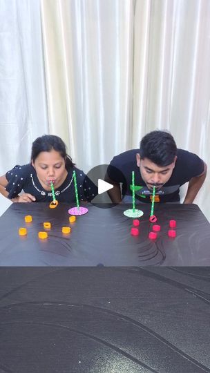 two people sitting at a table playing an interactive board game with colored dices on it