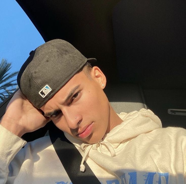 a young man sitting in the back seat of a car wearing a hat and tie