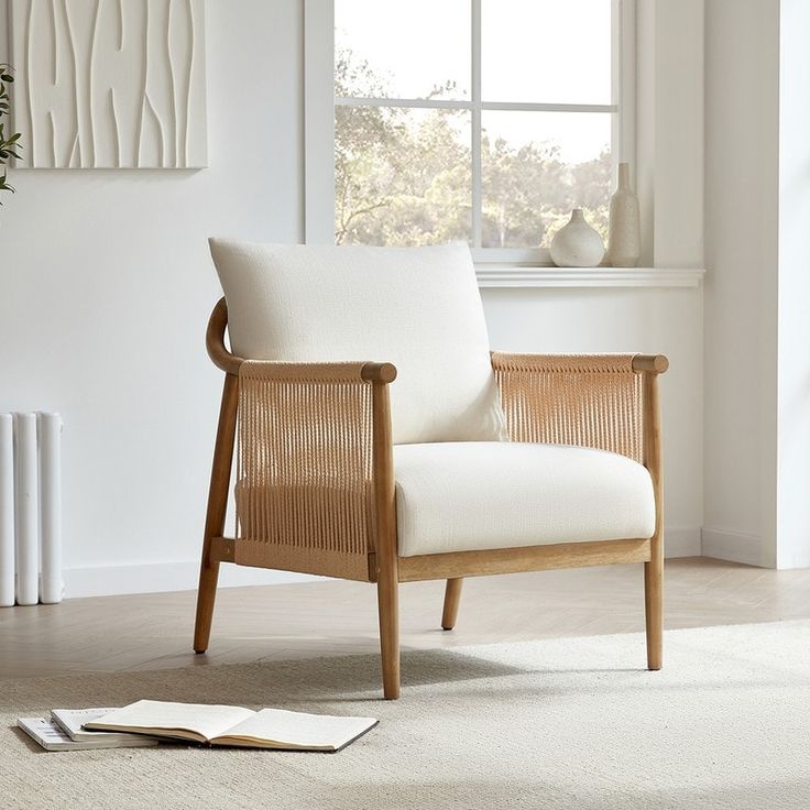 a white chair sitting in front of a window next to a book on the floor