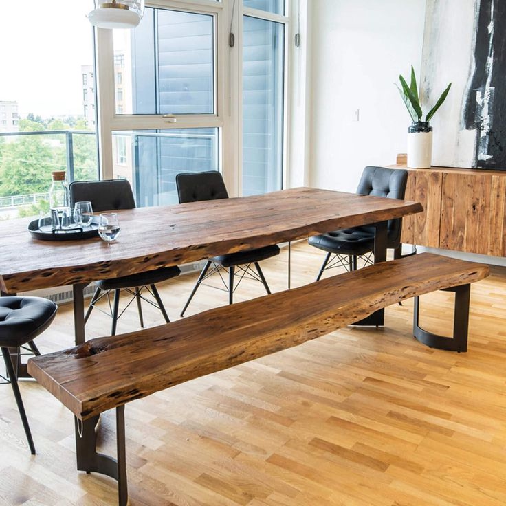 a wooden table with two benches in front of it and a large window behind it