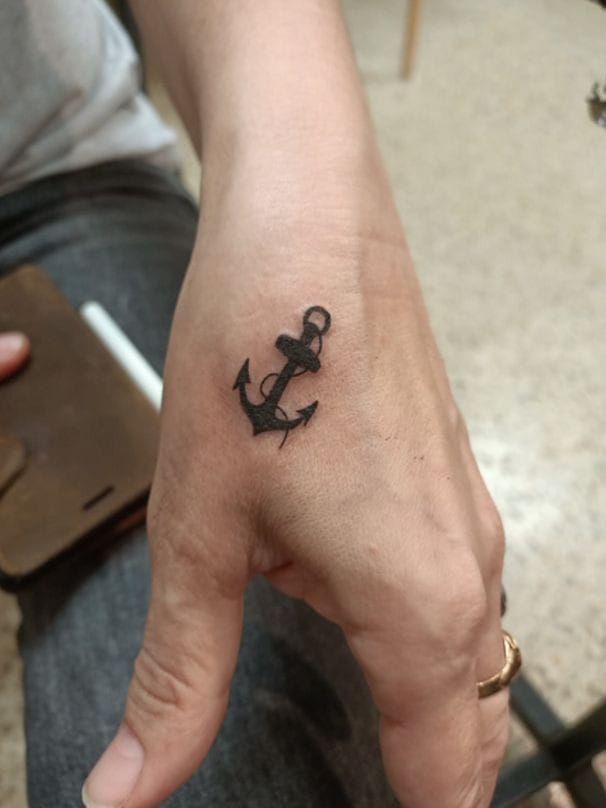 a small anchor tattoo on the left hand