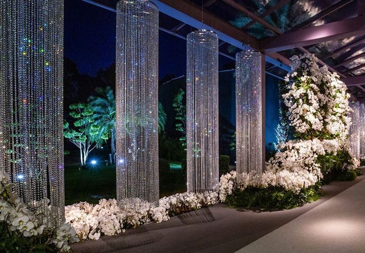 the walkway is lined with crystal columns and white flowers on each side, along with hanging chandeliers