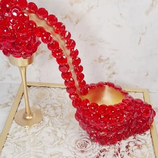 red beads pouring out of a bowl into a gold cup on top of a table