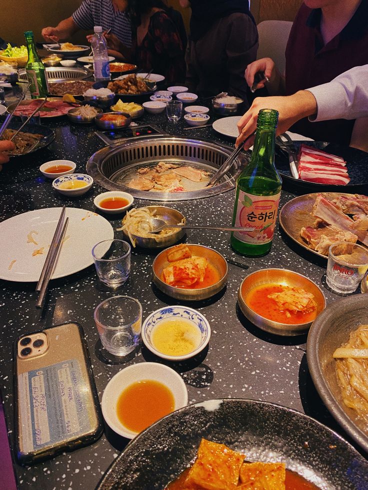 people are sitting at a table full of food and condiments, with plates on the table