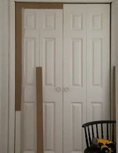 a room with two white doors and a black chair in front of the closet door