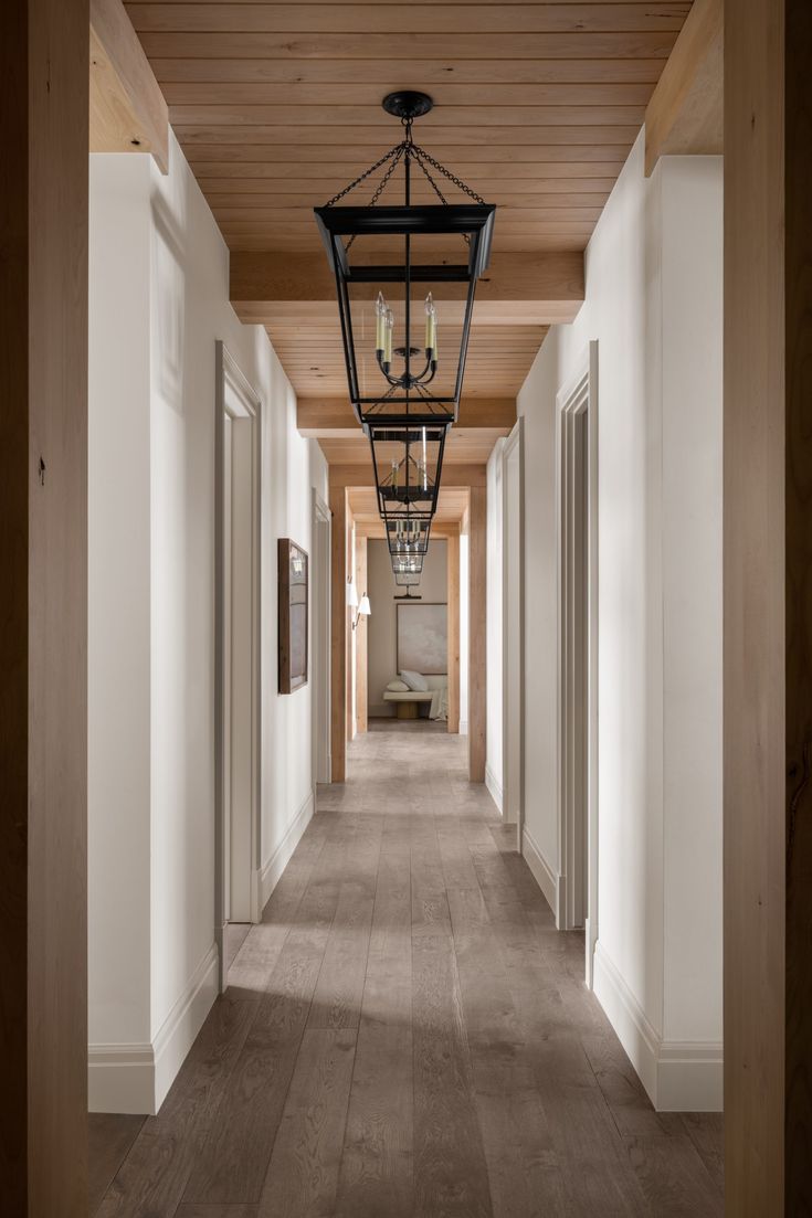 a long hallway with two lamps hanging from the ceiling and wood paneling on the walls