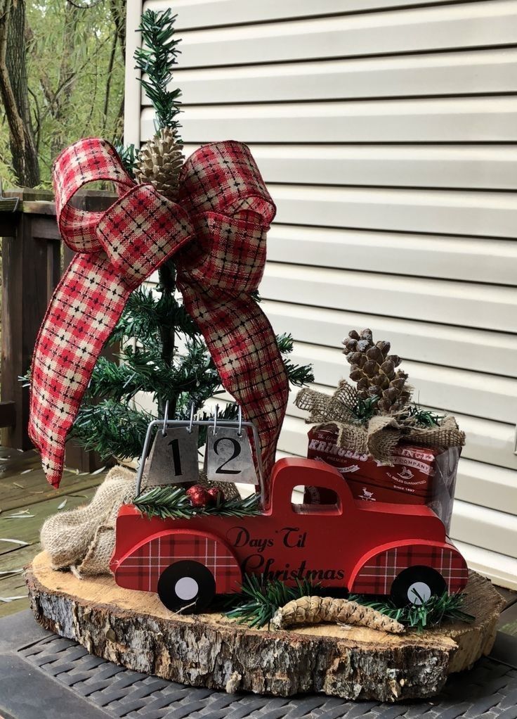 a red truck with a christmas tree in the back sits on top of a log