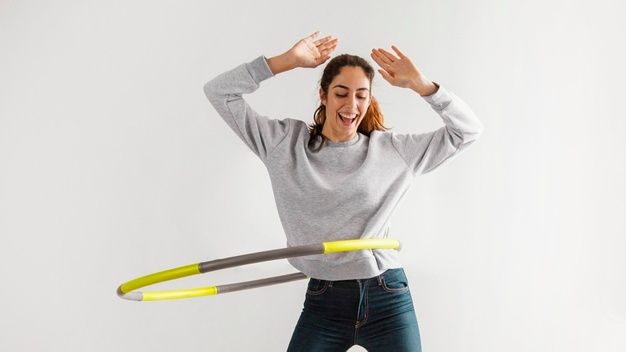 a woman is playing with a hula hoop while standing in front of a white background