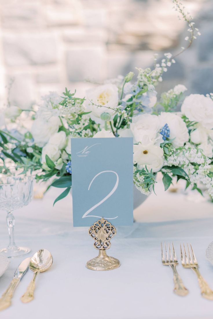 the table is set with silverware and white flowers