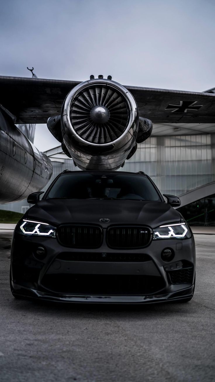 a black car parked in front of an airplane