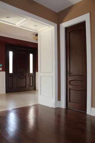 an empty living room with wood floors and white trim on the walls, along with two wooden doors