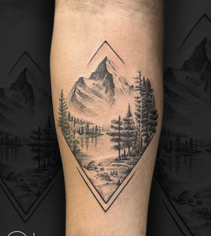 a tattoo on the leg of a person with mountains and trees in the background,