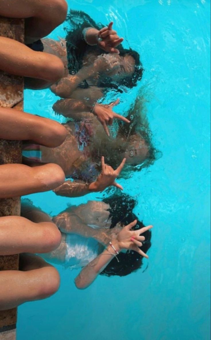 several people are swimming in a pool with their hands up to the water's surface