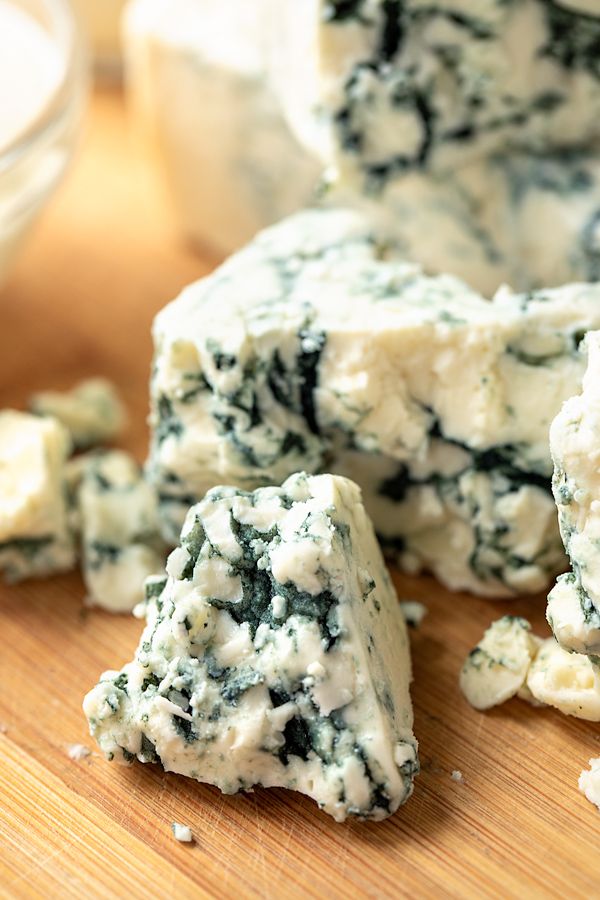 several pieces of blue cheese sitting on top of a wooden cutting board